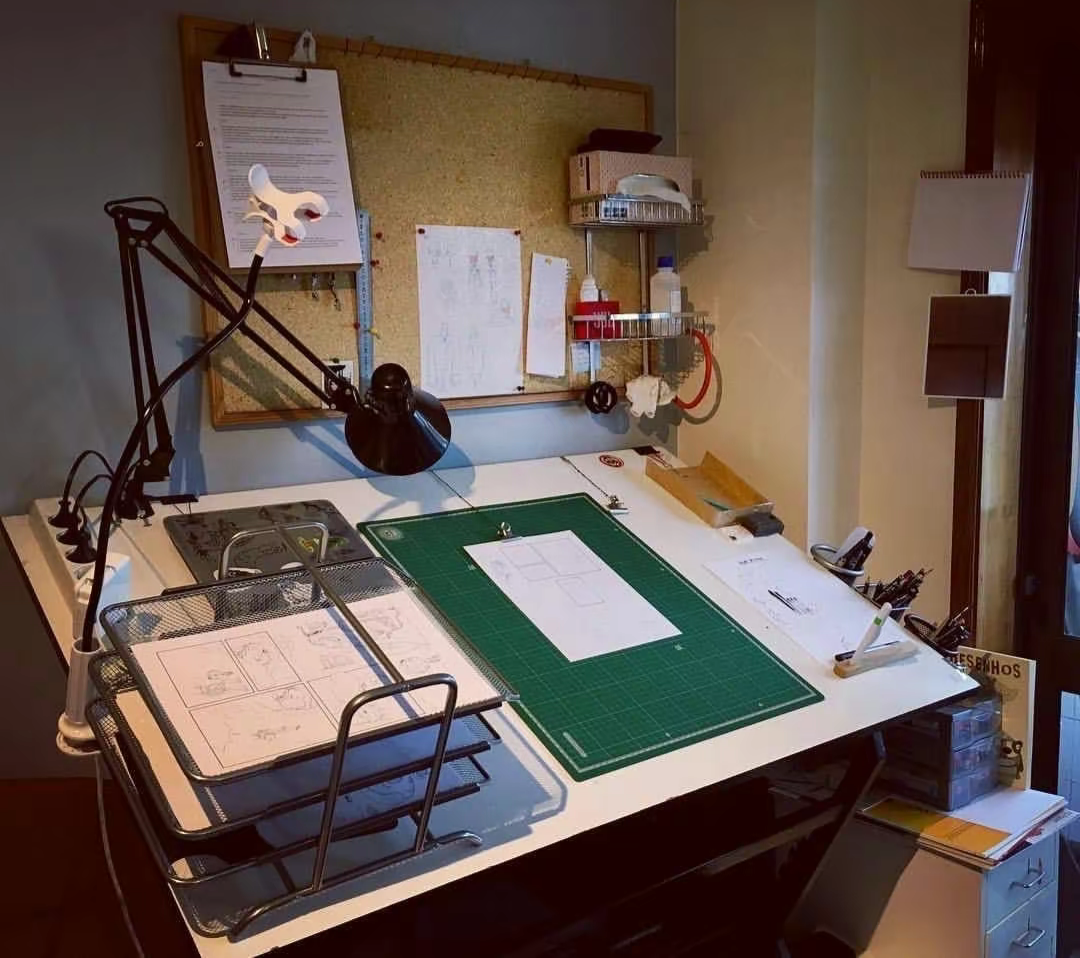 Overhead view of an architecture studio workspace with drawings, models and a laptop on the table